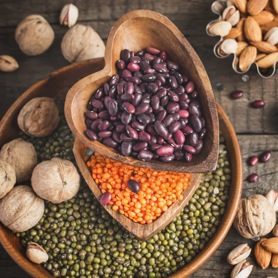 Variedad de legumbres y nueces en recipientes de madera.