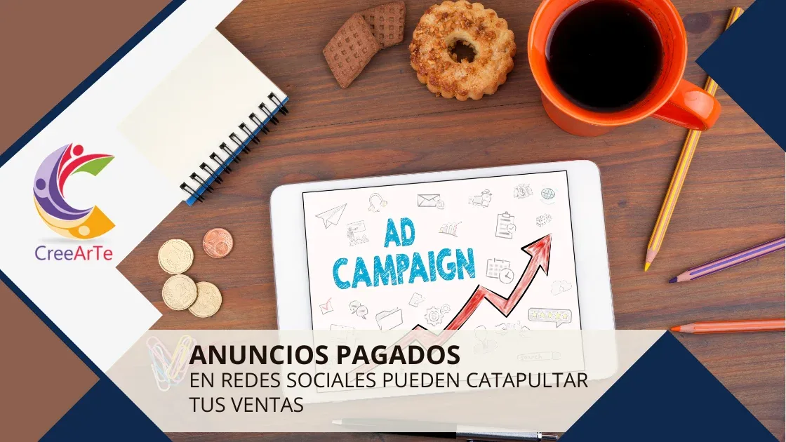 Tableta con la palabra "Ad Campaign" junto a una taza de café, monedas y un cuaderno sobre una mesa de madera.