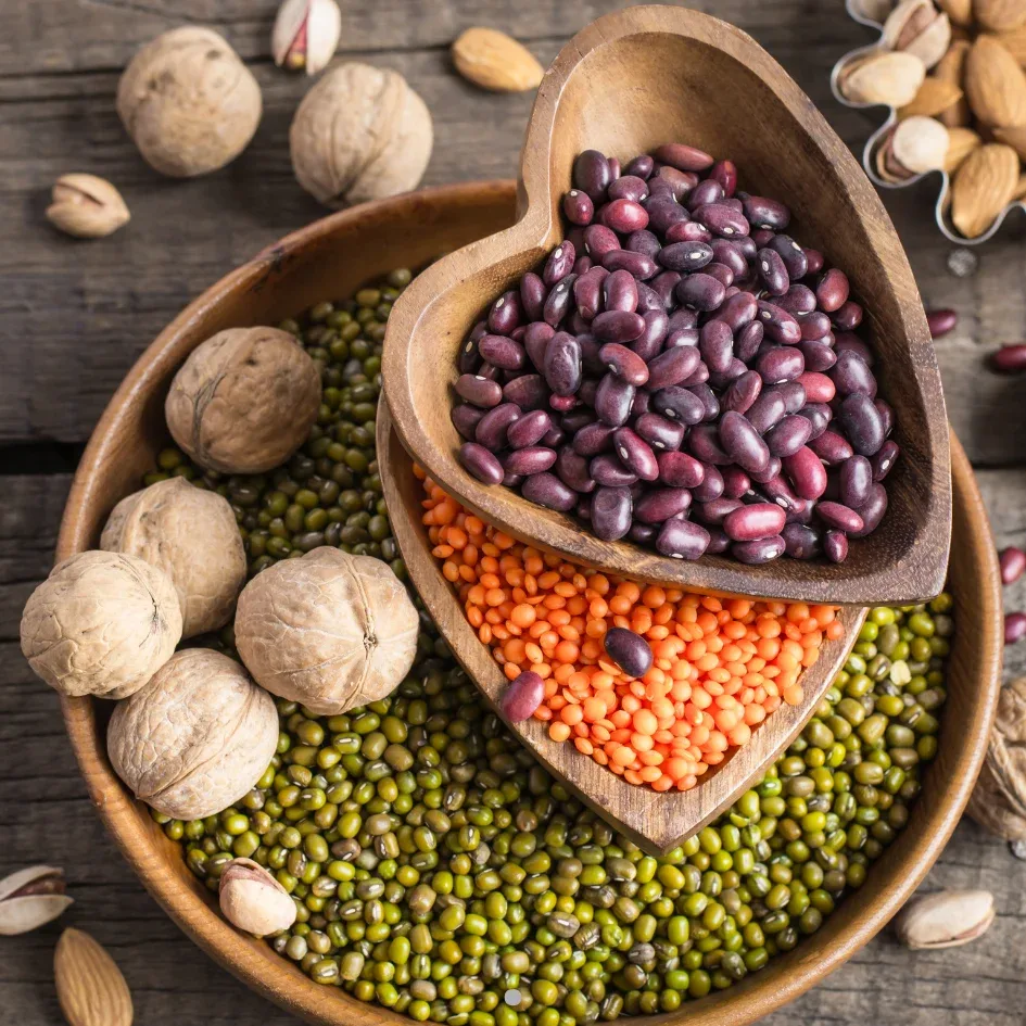 Variedad de proteínas vegetales incluyendo frijoles, lentejas rojas y nueces, dispuestos en tazones de madera sobre una mesa rústica.